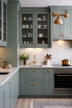 a kitchen with green cabinets and gold accents