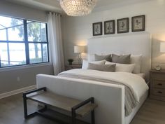 a bedroom with a large bed, two nightstands and a chandelier hanging from the ceiling