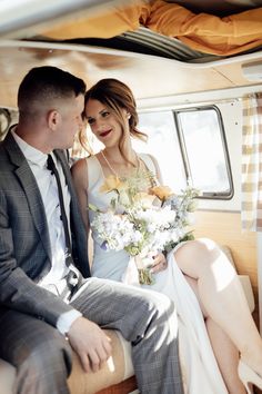 a bride and groom sitting on the back of a bus