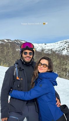 a man and woman standing on top of a snow covered slope