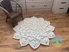 a white crocheted doily sitting on top of a wooden floor next to a chair