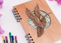 a wooden notebook with an image of a bird on it and colored crayons next to it