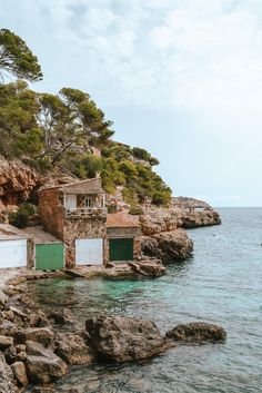 people swimming in the ocean next to some rocks and buildings with green doors on them