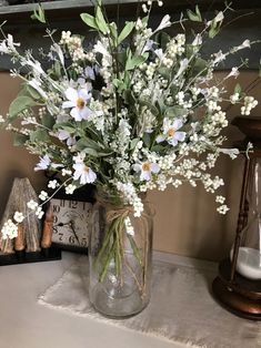 a vase filled with lots of white flowers on top of a table next to a clock