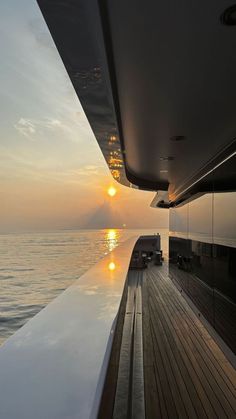 the sun is setting over the water from a boat on the ocean with wood decking