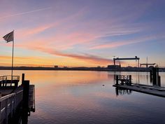 the sun is setting over the water and some docks