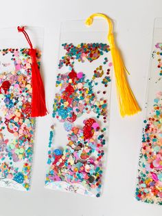 three bookmarks decorated with confetti and tassels