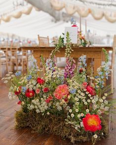 an arrangement of flowers and greenery in front of a table