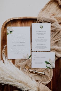 the wedding stationery is laid out on a wooden platter with fur and flowers