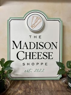 the madison cheese shoppe sign is next to some potted plants on a table