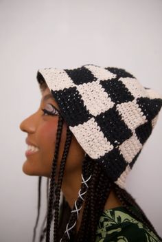 a woman wearing a black and white crochet hat with braids on her head