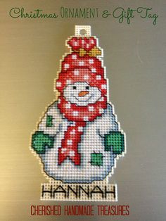 a cross stitch christmas ornament and gift tag with a snowman on it