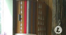 an assortment of colored pencils hanging on a wooden wall next to a potted plant