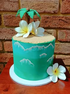 there is a green cake with white flowers on the top and palm tree in the middle