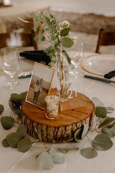 a wooden table topped with a vase filled with flowers and greenery on top of it