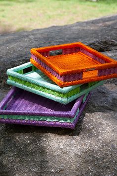 three different colored trays sitting on top of a rock