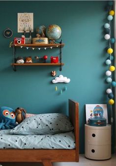 a child's bedroom with blue walls and toys on the shelf above the bed