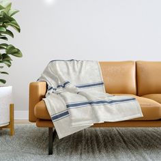 a couch with a blanket on it next to a potted plant