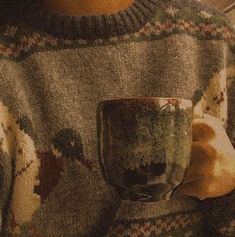 a person wearing a sweater holding a cup