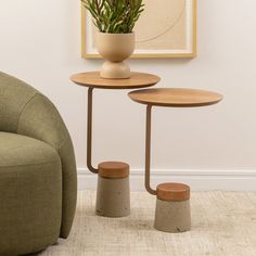 two small tables sitting next to each other in front of a green chair and potted plant