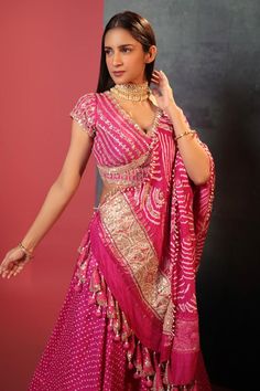 a woman in a pink and gold sari with her hands on her hip, posing for the camera