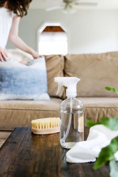 a woman in white shirt cleaning a table with a brush and cleaner bottle on it