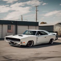 a white muscle car parked in a parking lot