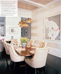 the dining room table is surrounded by white chairs and beige upholstered arm chairs