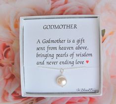 a mother's necklace with a pearl on it in a gift box next to pink flowers