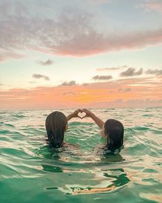 two people in the water making a heart with their hands