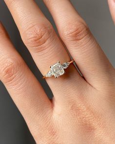 a woman's hand with an engagement ring on top of her finger, showing the side stones