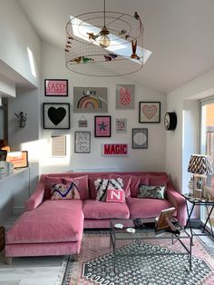 a living room filled with pink couches and pictures on the wall above their windows