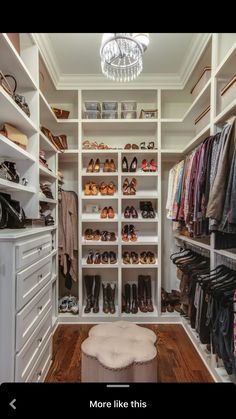 a walk in closet filled with lots of clothes and shoes on shelves next to a chandelier