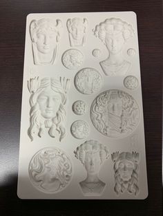 a cookie sheet with many different faces and heads on it's side, sitting on top of a table