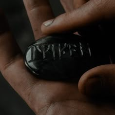 a hand holding a black rock with the word spirit written on it in cursive writing