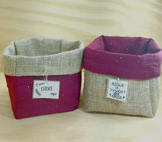 two small baskets with labels on them sitting on a wooden table next to each other