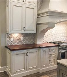 a kitchen with white cabinets and wood counter tops in the middle of an island area