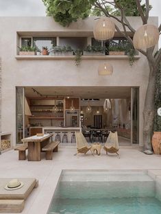 an indoor swimming pool with lounge chairs and tables next to it in front of a house