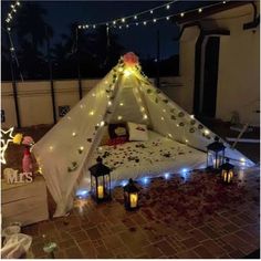 a bed with lights on it and some pillows in the room next to it that is decorated like a teepee