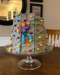 there is a cake that looks like someone climbing on a rock wall with colorful candies