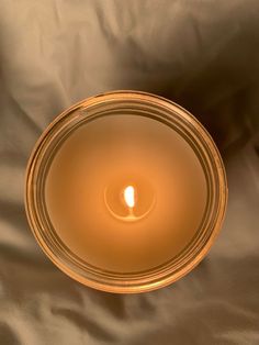 a lit candle sitting on top of a white sheet