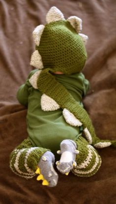 a crocheted frog is sitting on a bed with his legs crossed and head turned to the side