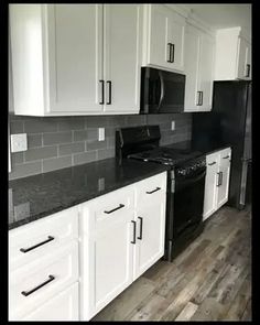 a kitchen with white cabinets and black appliances