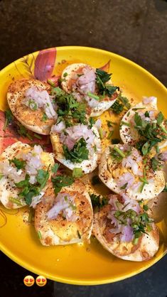 a yellow plate topped with scallops covered in toppings on top of a table