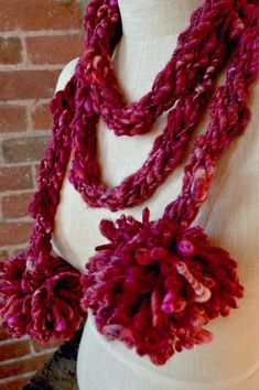 a mannequin wearing a red scarf with pom - poms on it