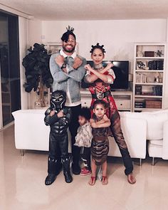 a man and two children are standing in front of a white couch with costumes on