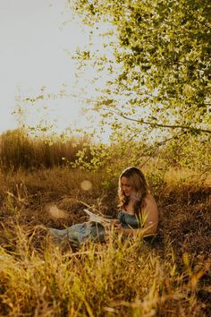 a woman sitting in the grass reading a book