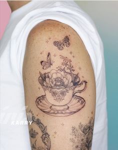 a woman with a tattoo on her arm has a teacup and butterflies in it