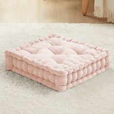 a pink dog bed sitting on top of a white rug