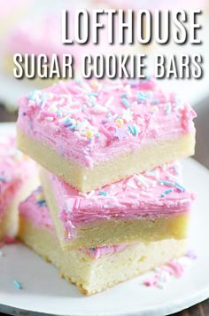 three sugar cookie bars with pink frosting and sprinkles stacked on top of each other